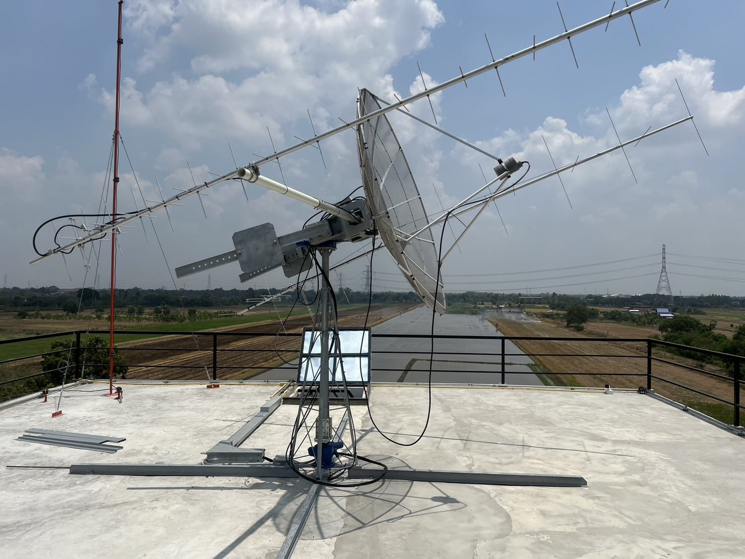 An EOS Orbit ground station antenna on Thai soil with rice fields behind it